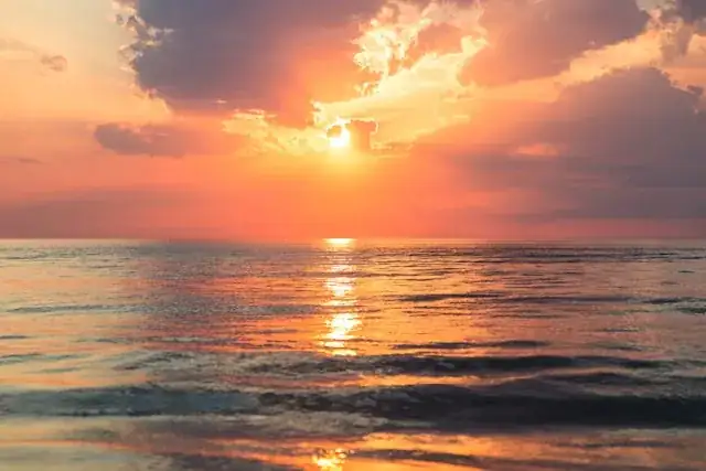 Sunset cruise guests on the deck of a charter boat watching an orange sky over the Pompano Beach coastline