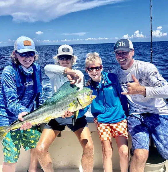 First-time angler holding a rod on the deck of a Pompano Beach sportfishing charter with the mate coaching beside him