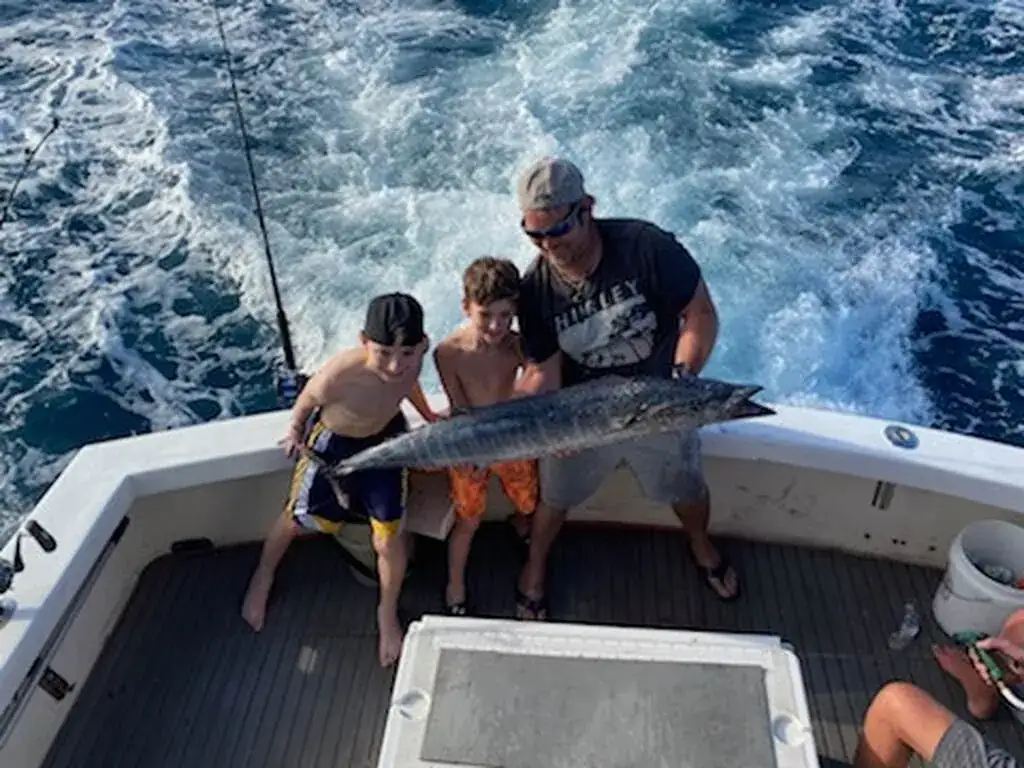 Child holding a freshly caught snapper with a smiling parent aboard a family fishing charter near Pompano Beach