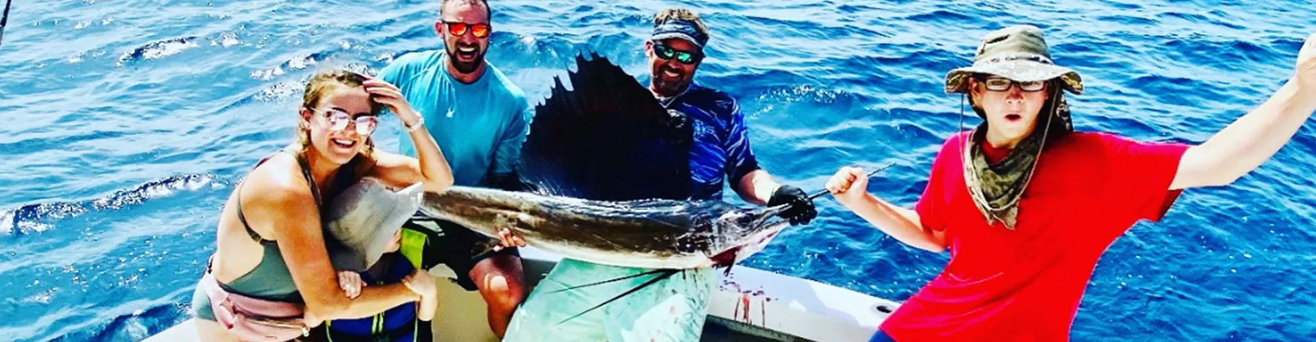 Anglers holding a sailfish boatside aboard Don't Panic off Pompano Beach